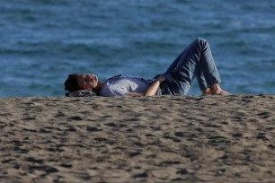 A man enjoying the sun on the beach during warm weather in Malaga, Spain.