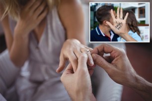 Man putting engagement ring on woman's hand.