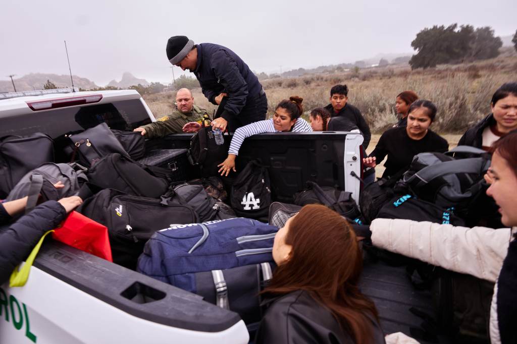 Migrants retrieve their bags as they are processed by US Customs and Border Protection officers after they crossed into the US on Feb. 20, 2024.