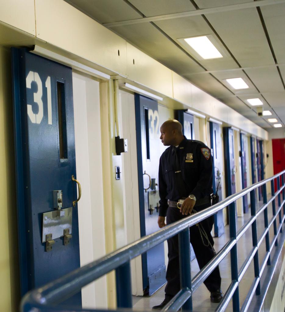 A correction officer walks a cell block. 