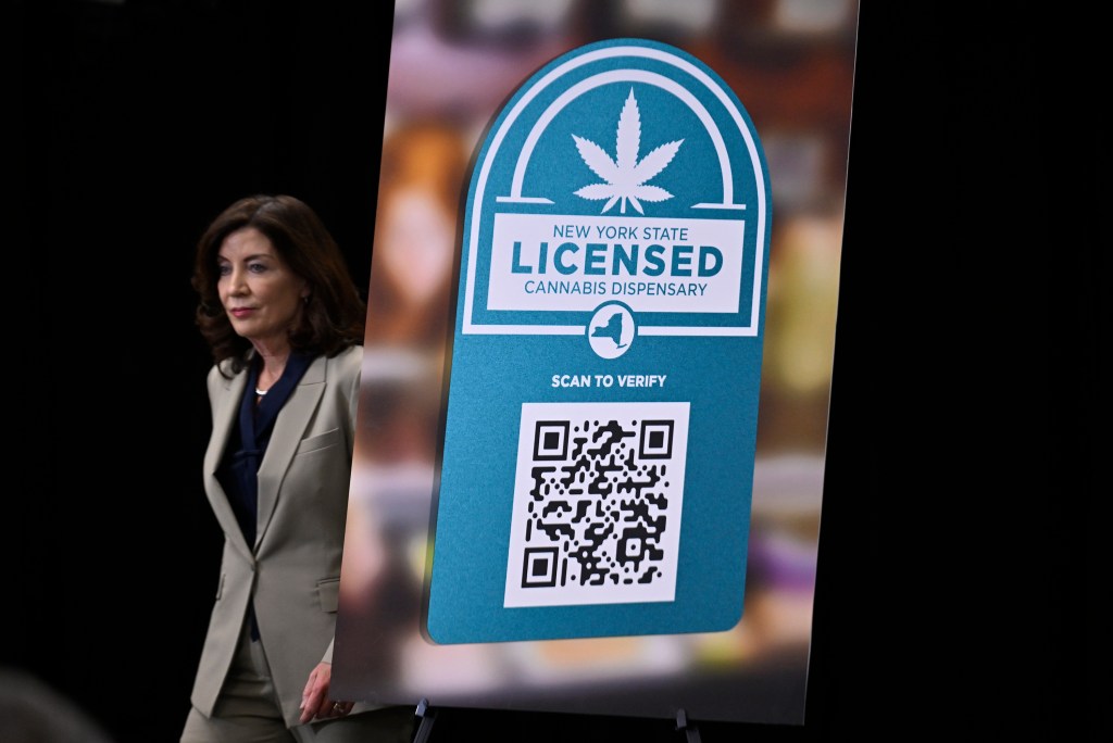 Kathy Hochul stands at the Department of Taxation and Finance in Brooklyn with a sign in front of her announcing NYS cannabis enforcement.