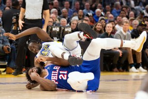 Golden State Warriors forward Draymond Green (23) falls over Philadelphia 76ers center Joel Embiid (21) on an offensive foul by Embiid during the first half