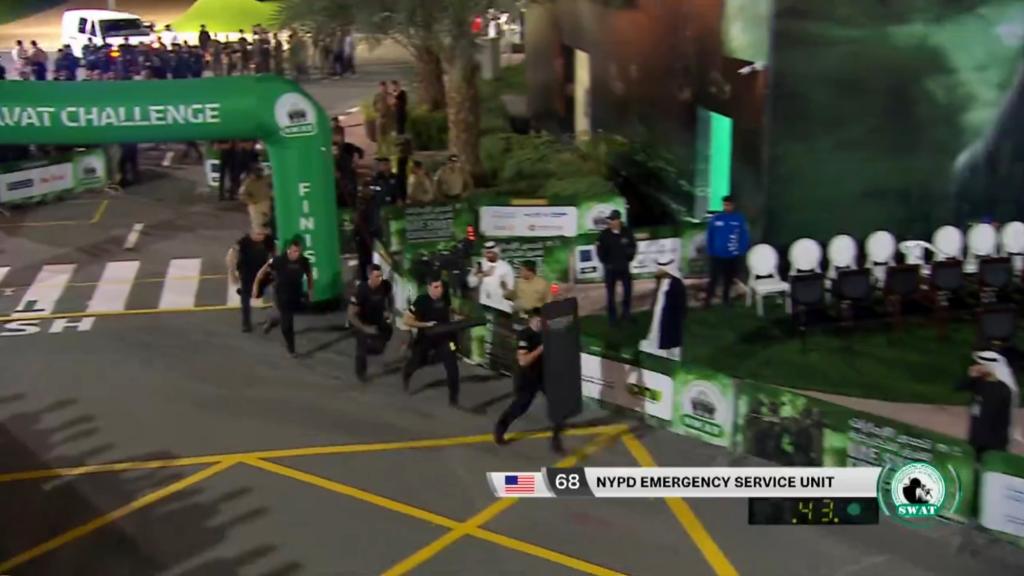 NYPD Emergency Services Unit members running in front of a green archway during a competition in Dubai.