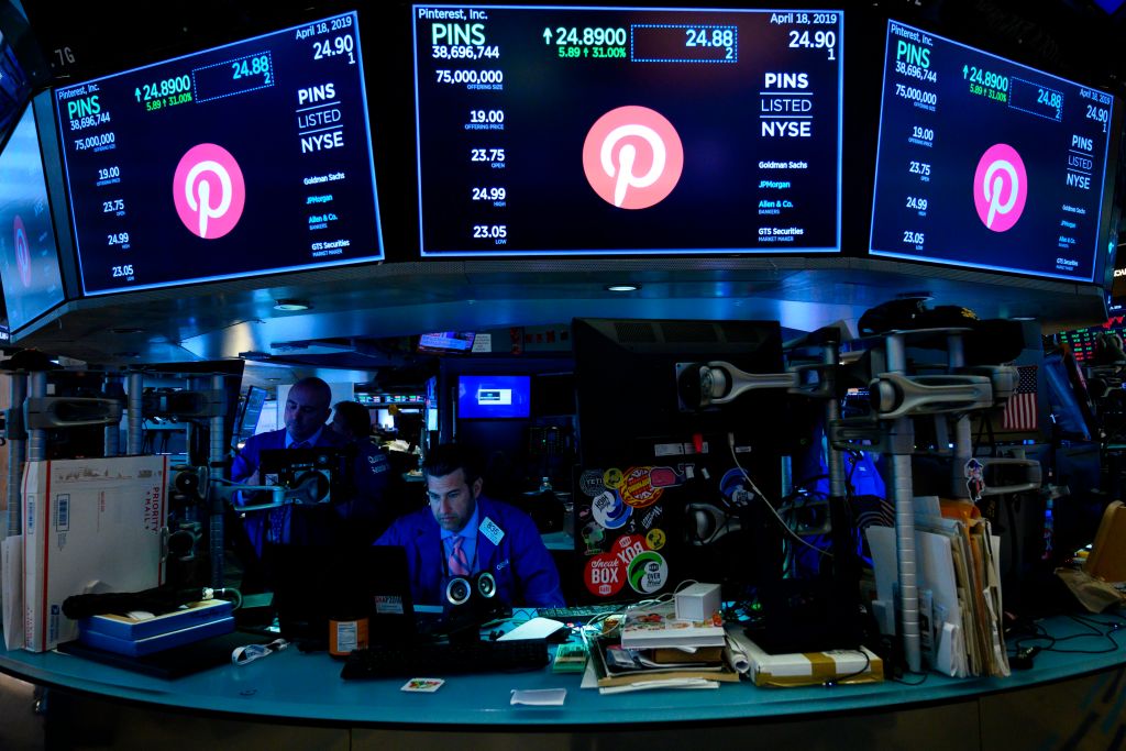 Traders working at NYSE with Pinterest logo displayed on screens during company's IPO.