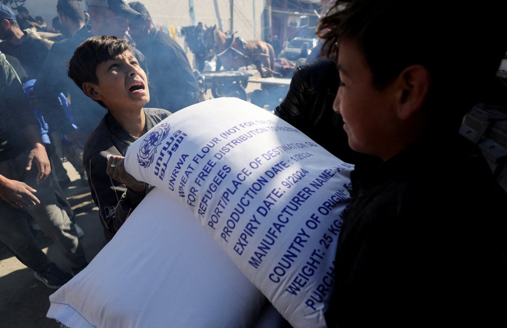 FILE PHOTO: Palestinians gather to receive bags of flour distributed by the United Nations Relief and Works Agency (UNRWA), amid the ongoing conflict between Israel and Palestinian Islamist group Hamas, in Rafah in the southern Gaza Strip February 1, 2024. REUTERS/Ibraheem Abu Mustafa/File Photo
