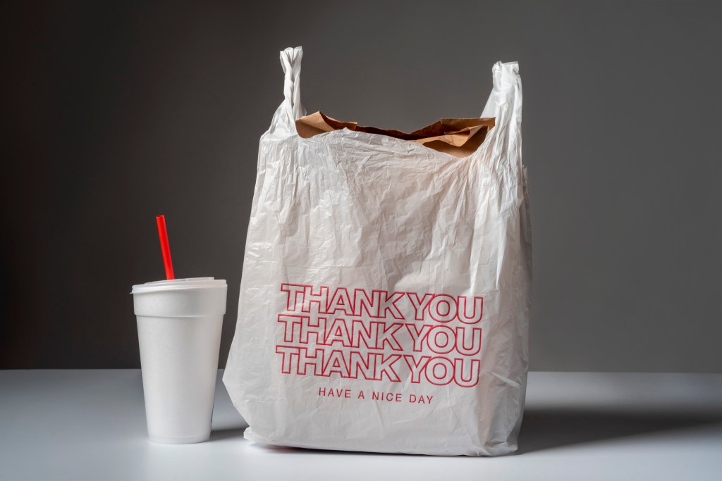 Trash from food delivery: styrofoam cup, plastic straw, paper sack & plastic bag. Some items can't be recycled. [Filename: photograph-trash-food-delivery-take-76044848]