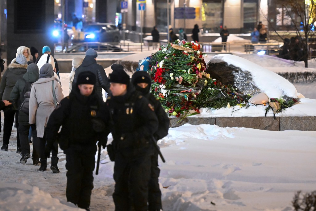 Police guard an area as people lay flowers in tribute to Alexei Navalny on Friday.