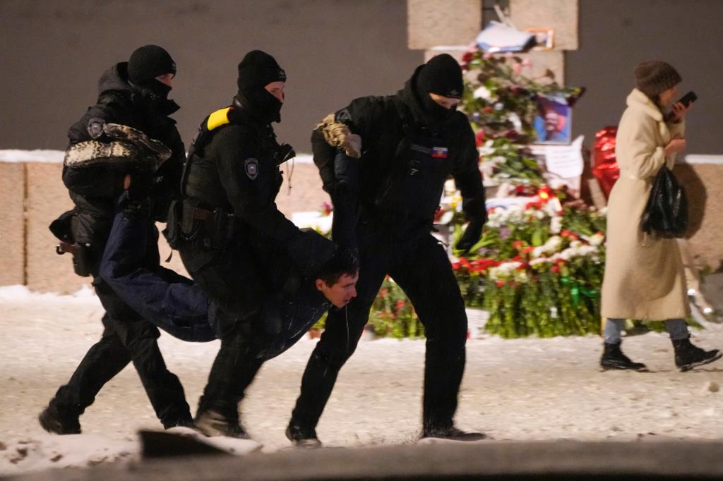 Russian police detain a man for laying flowers to Alexei Navalny at the Memorial to Victims of Political Repression on Friday.