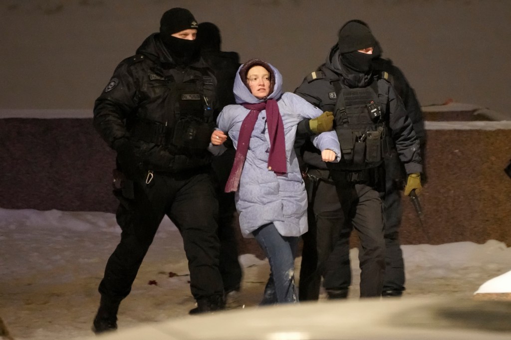 A woman is detained by police for laying flowers at the Memorial to Victims of Political Repression in tribute to Navalny on Friday.