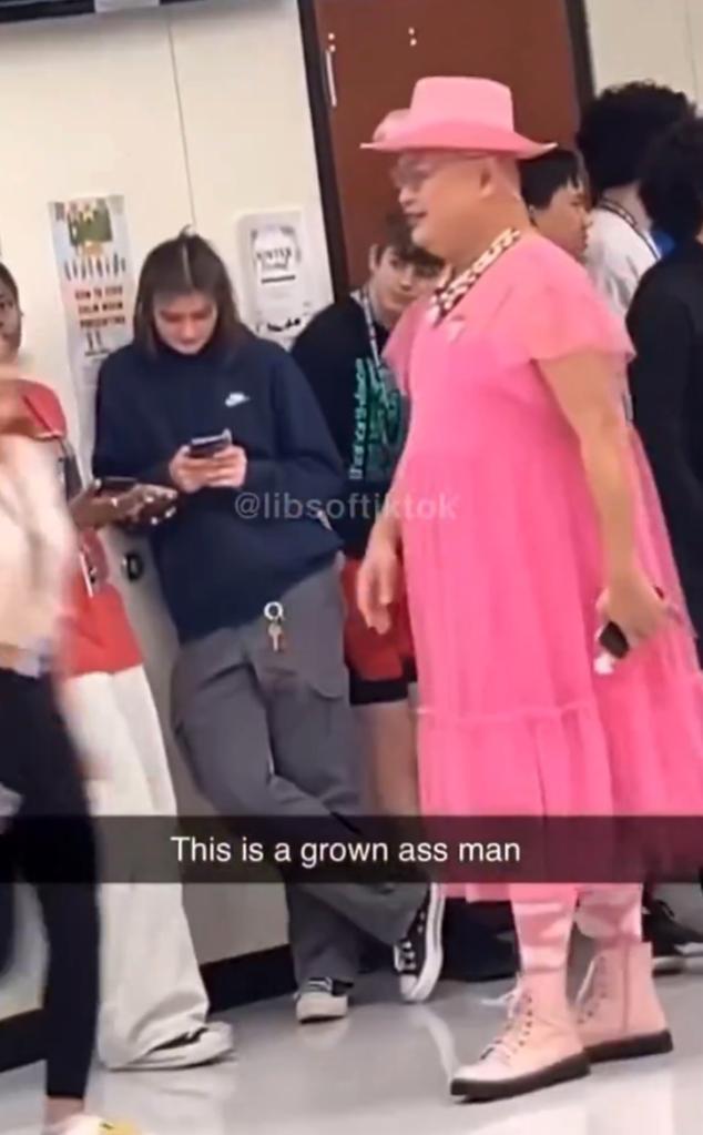 Social media screenshot showing Rachmad Tjachyad in pink Valentine's Day dress, hat and boots with students in school, caption reading "this is a grown ass man."