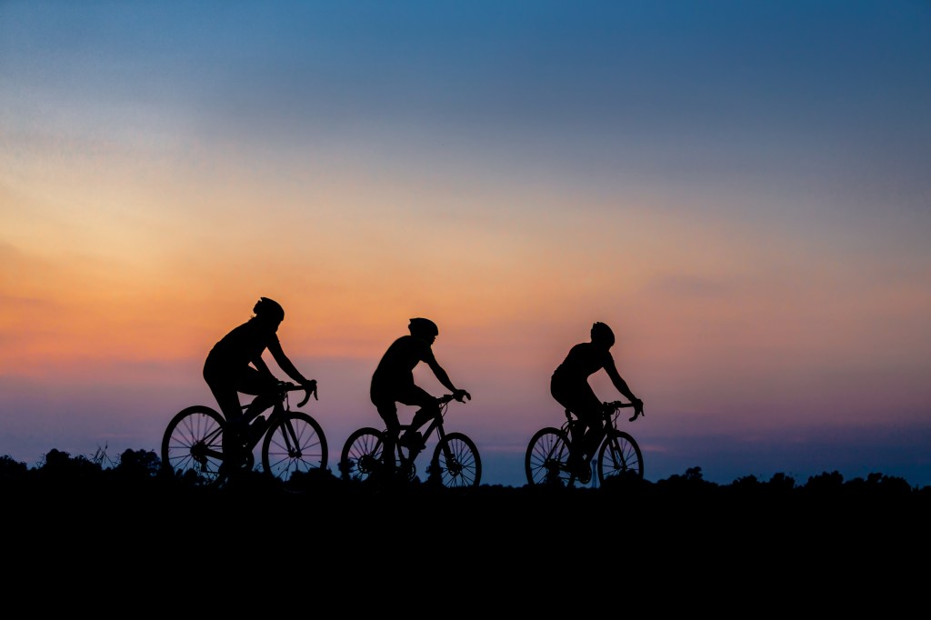 Silhouette of cyclist riding a bike during sunset.