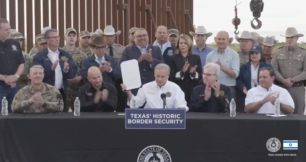 Texas Gov. Greg Abbott signs a border security bill at the border dence in Brownsville, Texas, Monday, Dec. 18, 2023