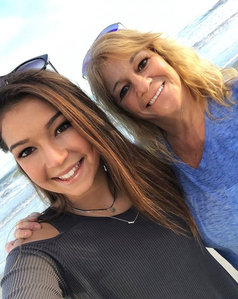 Jamie Komorski and her mother wrap their arms around eachother and smile for a selfie on a beach