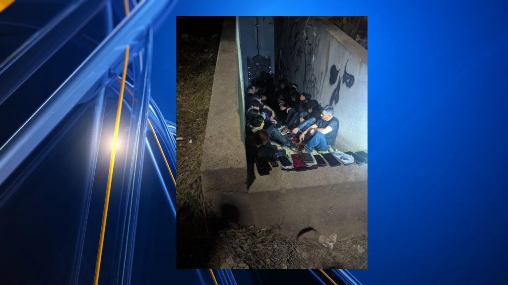 A group of 69 migrants sitting on a concrete wall in El Paso's storm drain system, intercepted and arrested by US Border Patrol agents.