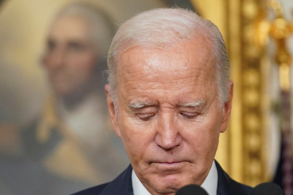 Joe Biden with his eyes closed, at a microphone