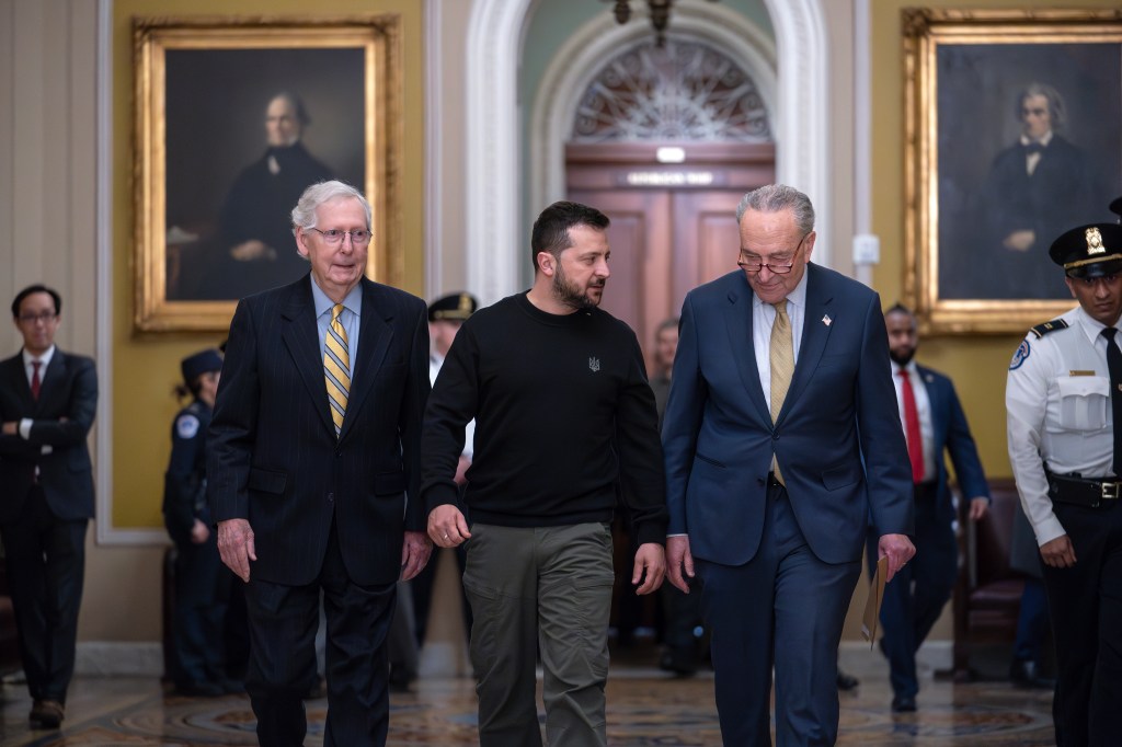 Ukrainian President Volodymyr Zelenskyy is in a hallway escorted by Senators Mitch McConnell and Chuck Schumer in Washington DC.