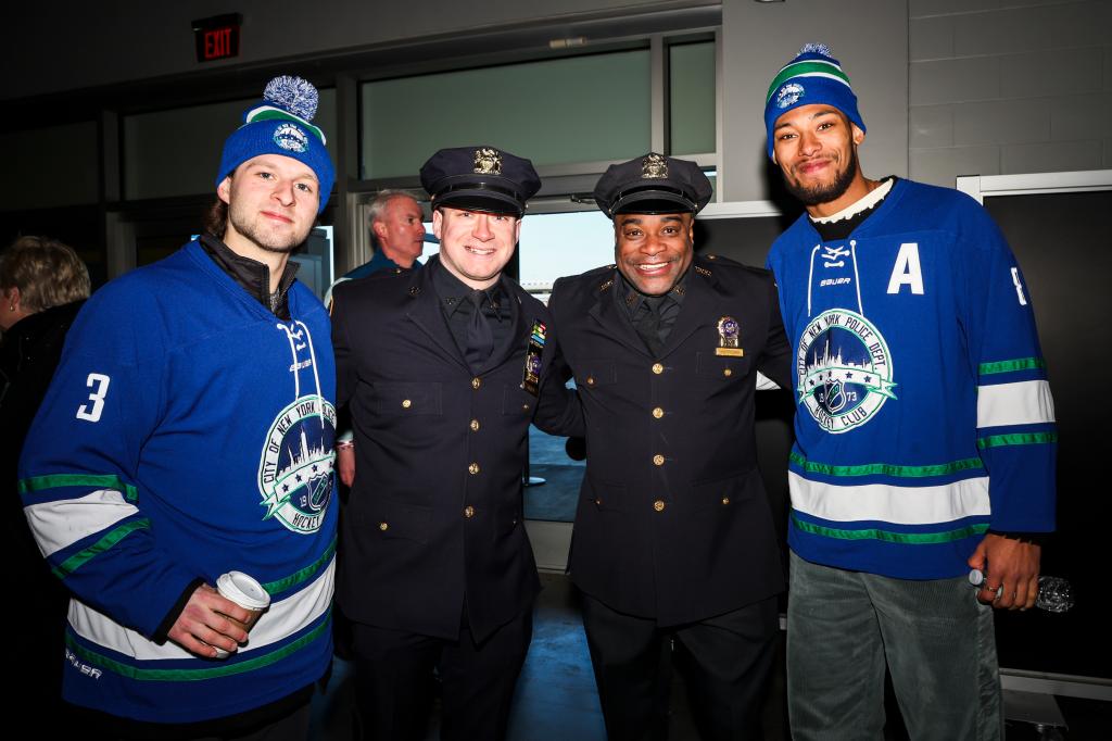 Zac Jones #6 and K'Andre Miller #79 of the New York Rangers pose with members of the FDNY and NYPD prior to the 2024 NHL Stadium Series game against the Islanders.