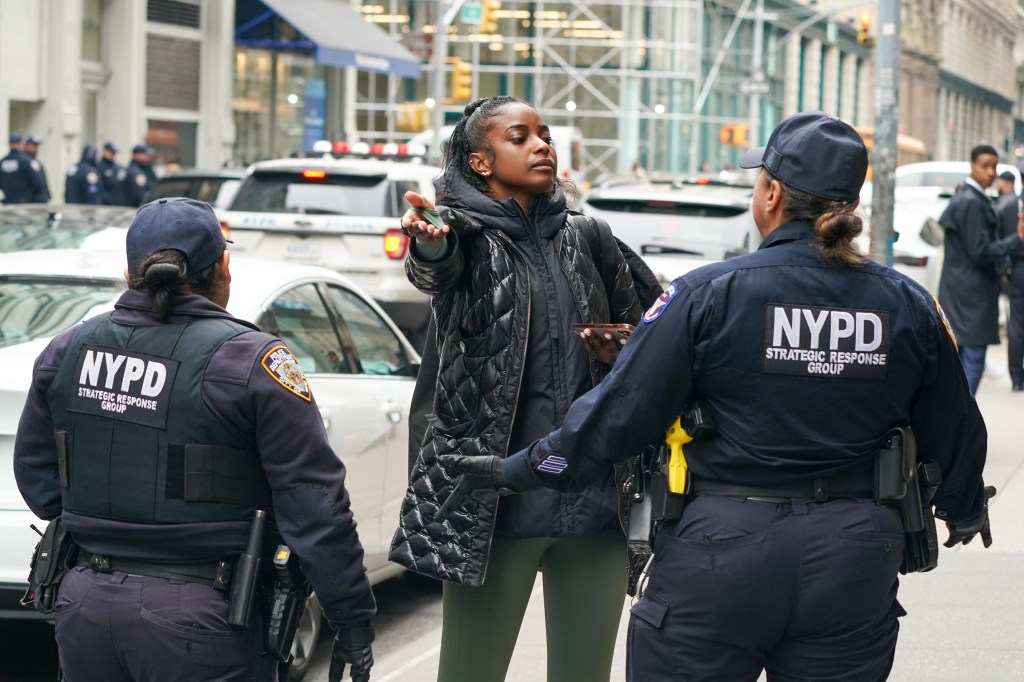 A woman standing in front of NYPD officers during a crowd control operation at Versace sample sale on 125 W 18st., Manhattan