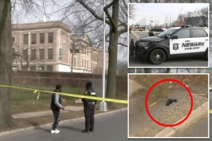 Police officer and man standing at the scene of a shooting outside West Side High School in Newark