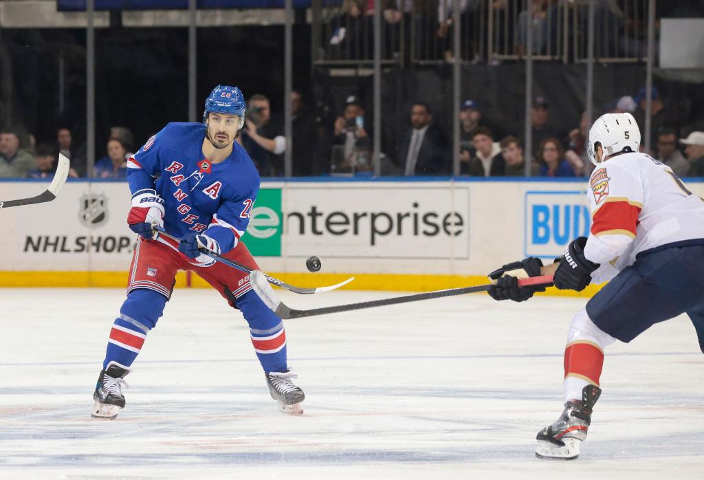 Chris Kreider #20 of the New York Rangerstips the puck with his stick as Aaron Ekblad #5 of the Florida Panthers tries to defend