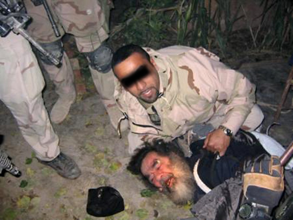 A photo of US troops dragging Saddam out of the hole near a farmhouse where he was hiding in Dec. 2003.