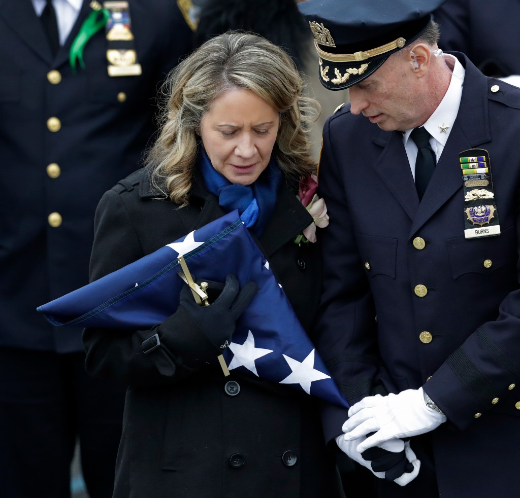Leanne Simonsen, the widow of Det. Brian Simonsen, holds the flag that draped his casket following his funeral at the Church of St. Rosalie in Hampton Bays, N.Y., Wednesday, Feb. 20, 2019.