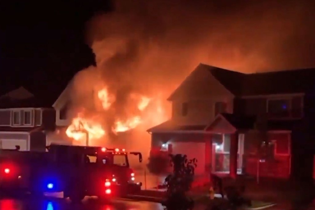 A house on fire with a fire truck nearby.