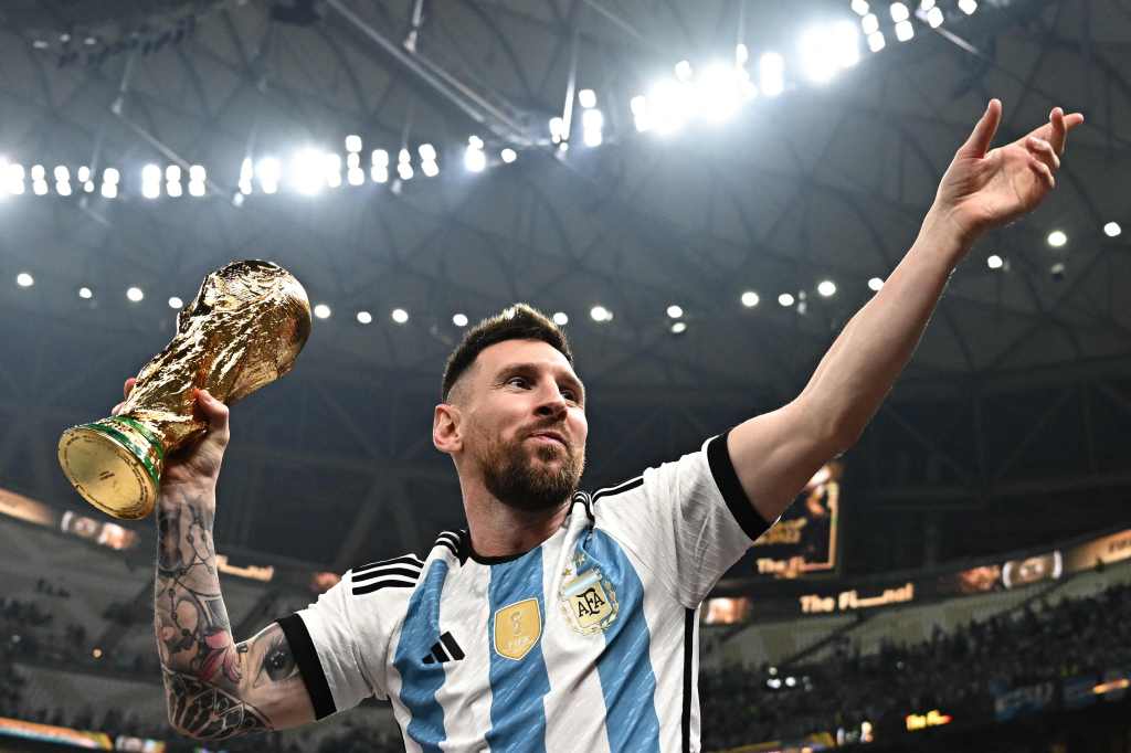 Lionel Messi holding FIFA World Cup Trophy in a stadium after Argentina won the 2022 World Cup final football match in Lusail, Qatar.