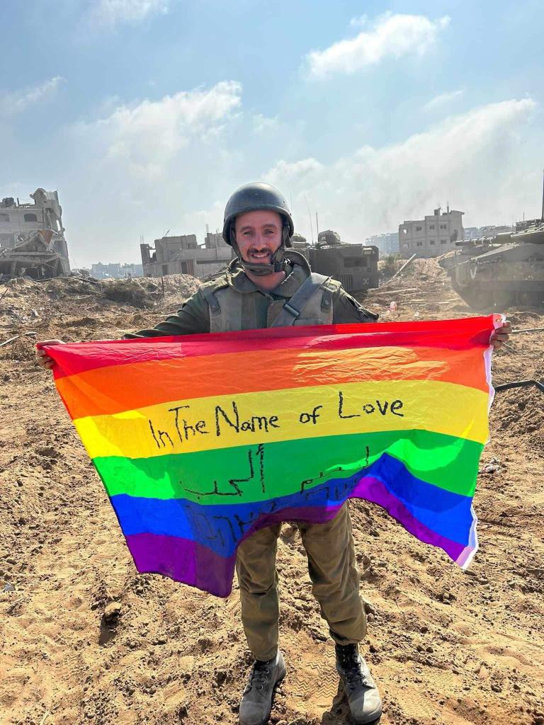 An IDF soldier in Gaza holding a pride flag