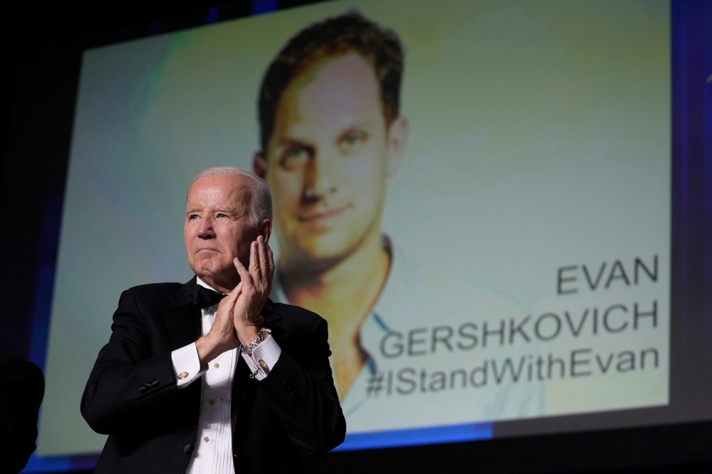 U.S. President Joe Biden speaking at the White House Correspondents' Association dinner, with an image of jailed journalist Evan Gershkovich in the background