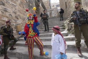 Jewish settlers dressed in costumes celebrate the Jewish holiday of Purim as soldiers secure the march in the West Bank city of Hebron, March 7, 2023.