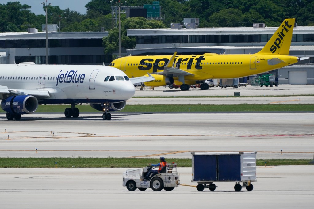 An Airbus A320 from JetBlue taxis on the runway beside a Spirit Airlines Airbus A320 at Fort Lauderdale-Hollywood International Airport.