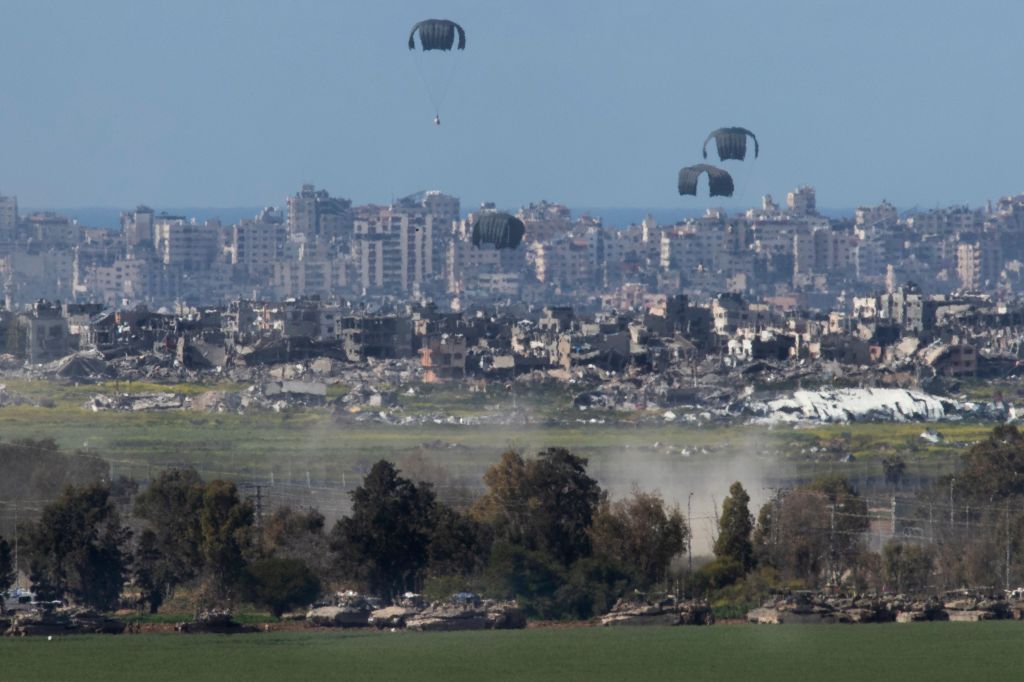 United States Air Force C-130 drops humanitarian aid by parachute over the northern Gaza Strip as seen from inside southern Israel on March 10, 2024. 
