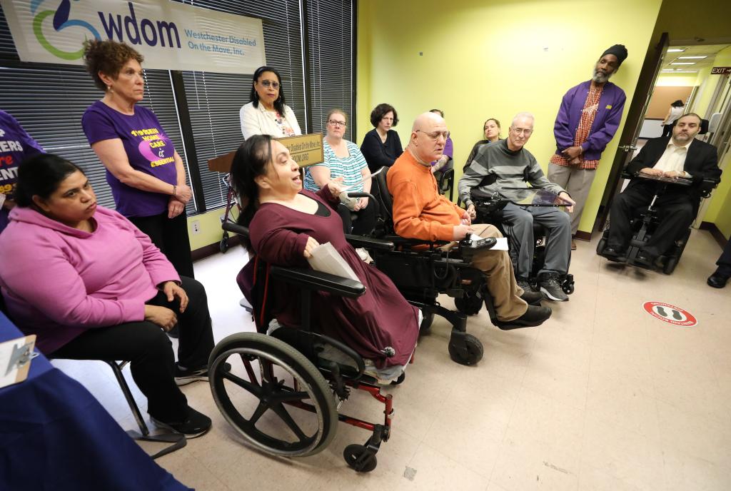 Several disabled people sit in wheelchairs at a press conference