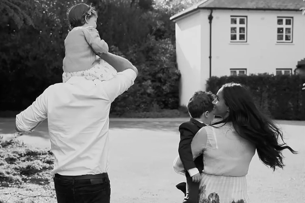 Prince Harry holding baby Archie on his shoulders outside.