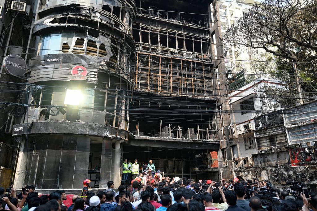 People gather near a commercial building a day after a fire accident, as firefighters and forensic expert inspect the site in Dhaka on March 1, 2024. 