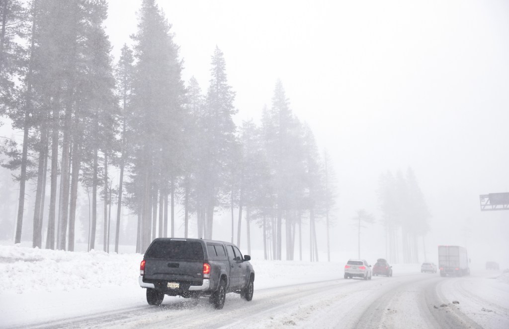 Vehicles drive as snow falls along Interstate 80 (I-80) in the Sierra Nevada mountains at the start of a powerful winter storm on February 29, 2024 near Kingvale, California.