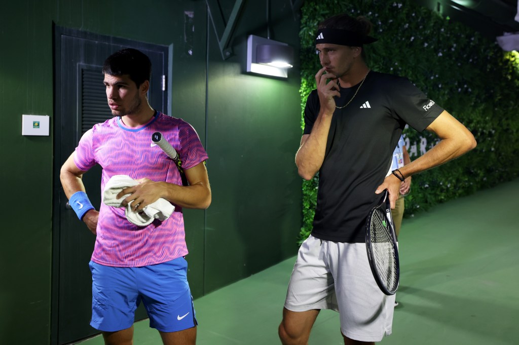 Carlos Alcaraz of Spain and Alexander Zverev of Germany watch on a TV monitor in the players tunnel after running in for cover from a swarm of bees that suddenly invaded the court whilst playing in their Quarterfinal match during the BNP Paribas Open.