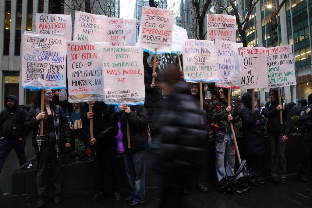 Pro-Palestinian demonstrators holding signs at the 'Flood Manhattan for Gaza' rally outside Radio City Music Hall during a Joe Biden fundraiser event