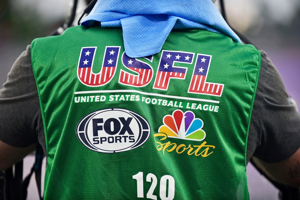 he FOX Sports and NBC Sports logos are displayed on the back of a USFL sideline vest during a USFL football game between the Michigan Panthers and Birmingham Stallions 