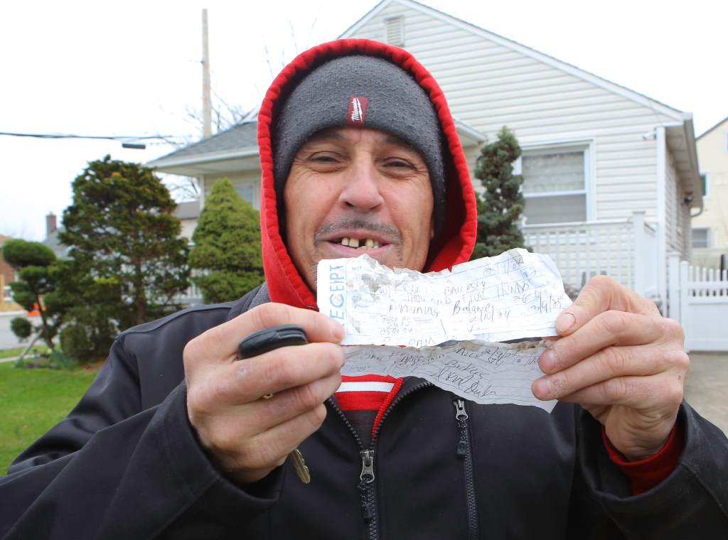 A tenant from the house holds up the receipt he received from Brian Rodriguez