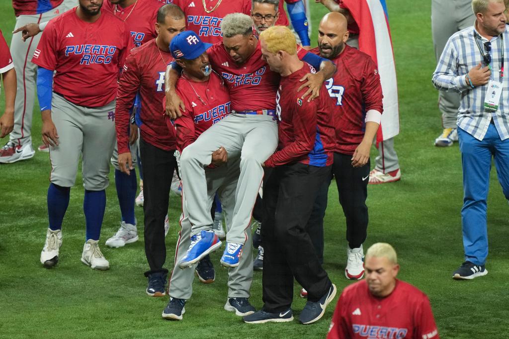 Edwin Diaz #39 of Puerto Rico is helped off the field after being injured during the on-field celebration after defeating the Dominican Republic during the World Baseball Classic