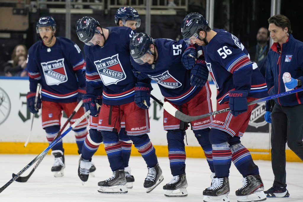 Rangers teammates help Ryan Lindgren (55) off the ice after he suffered a leg injury vs. the Islanders on Sunday.