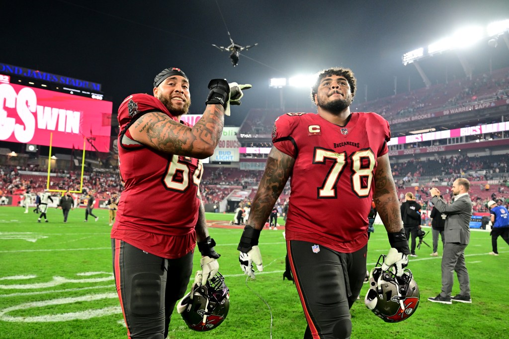 Aaron Stinnie #64 and Tristan Wirfs #78 of the Tampa Bay Buccaneers celebrate after defeating the Philadelphia Eagles in the NFC Wild Card Playoffs.