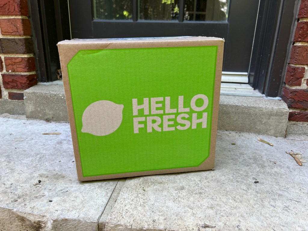 A green Hello Fresh delivery box on concrete.