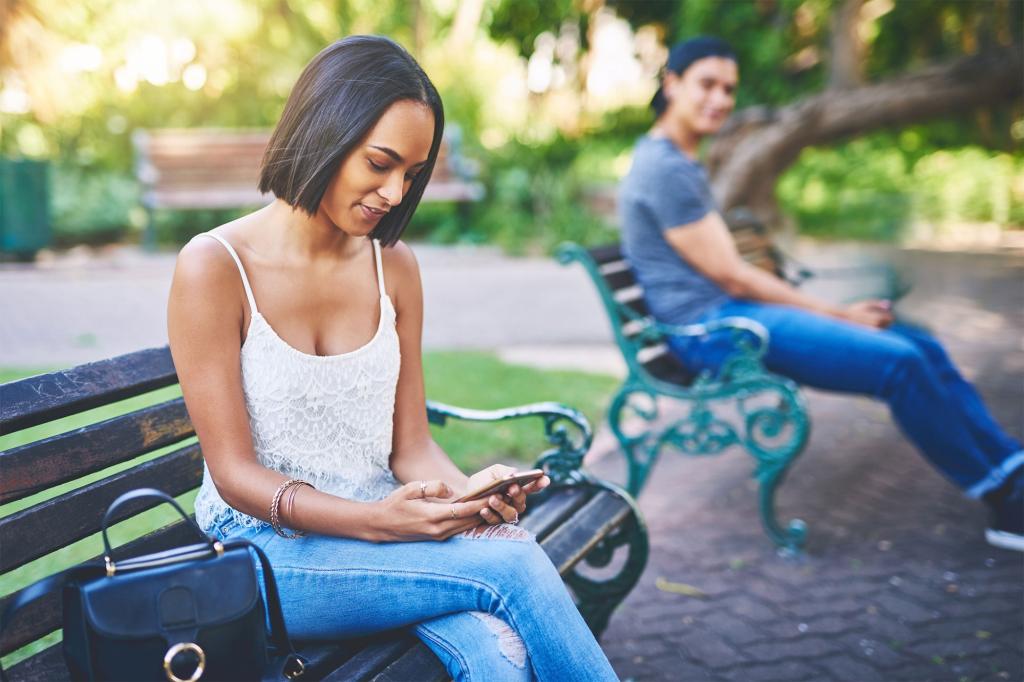 A woman using her phone while sitting on a bench.