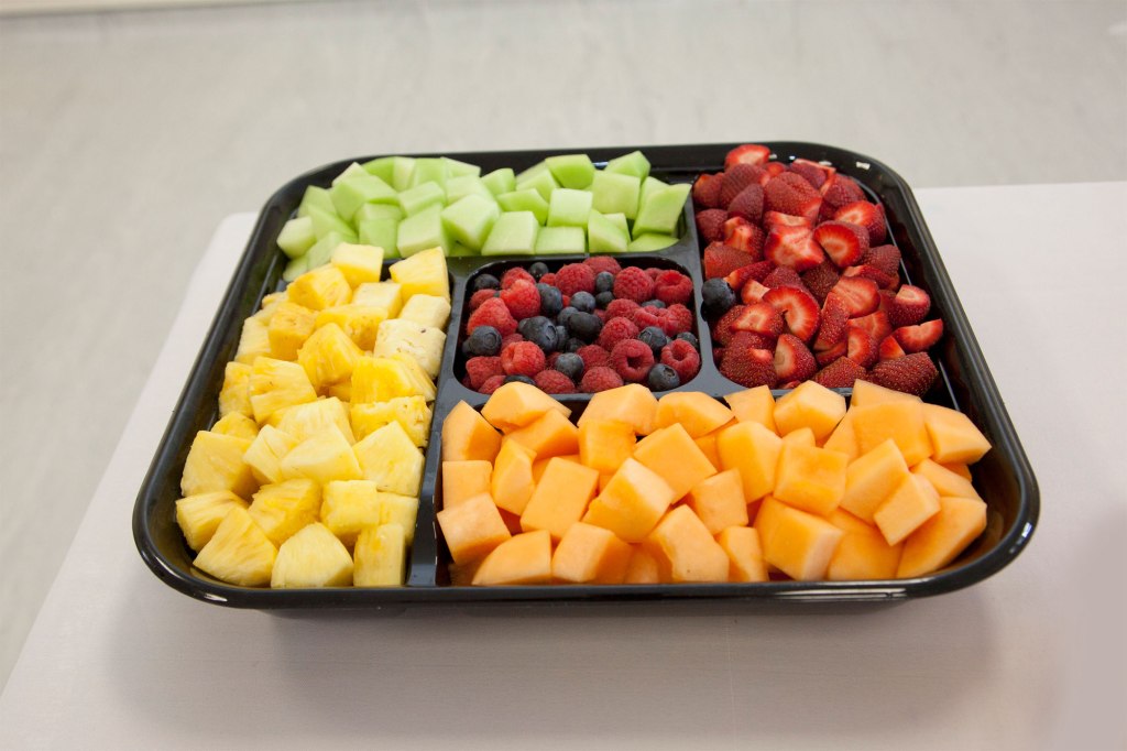 A tray of assorted fruits on a wooden table.