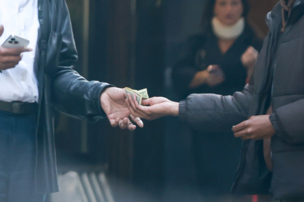 one person in a dark colored jacket hands money to another