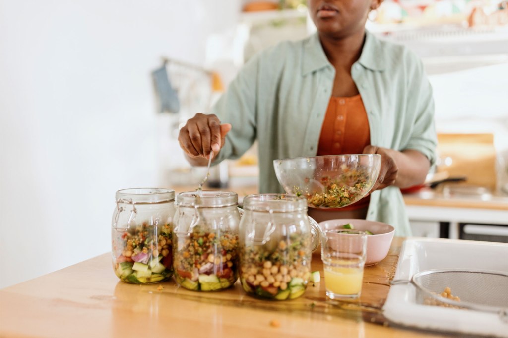 A woman mixing food in a jar, for proper storage, as suggested by Thomas.