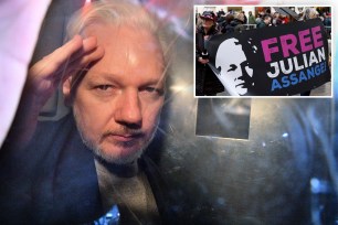 WikiLeaks founder Julian Assange gestures from the window of a prison van